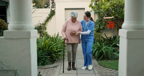 Senior Woman Walks with Healthcare Worker in Garden