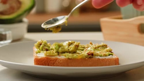 Avocado Toast Preparation with Spoon in Home