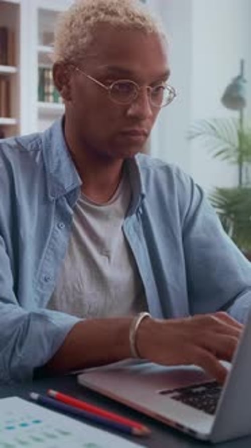 Young African American Person Focused on Work at Home Desk