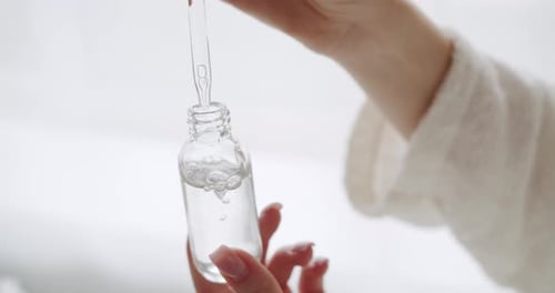Woman Holds Dropper Bottle with Serum Close Up