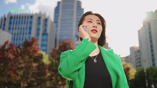 Confident and Carefree Korean Woman is Walking in City and Calling By Mobile Phone Portrait