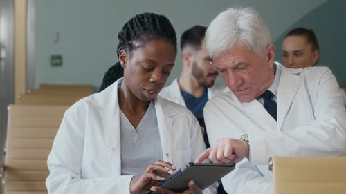 Female Doctor Using Tablet Discussing Presentation with Colleague in Auditorium