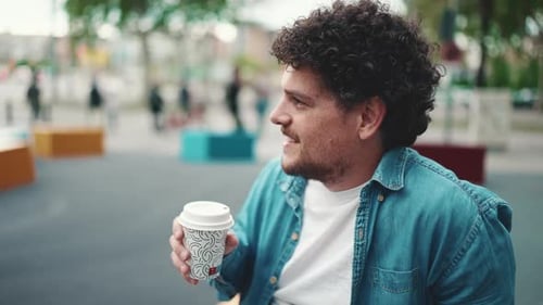 Close-up of man sitting and drinking coffee on busy street modern city background