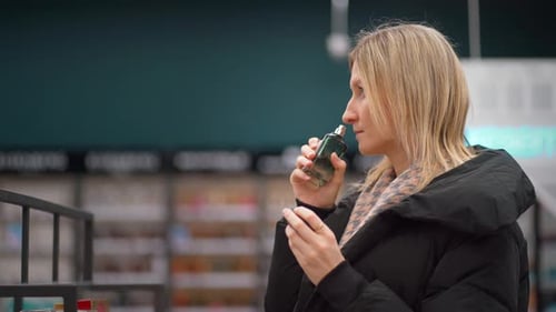 Woman smelling perfume in pharmacy or perfumery