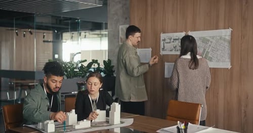 People Gather in an Office to Talk About a Project Looking at Maps and Sharing Their Thoughts While