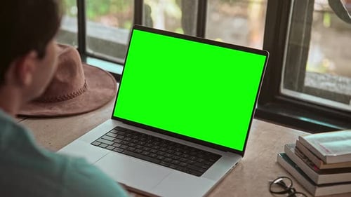 Hombre trabajando en una computadora portátil y mirando una videollamada en línea en pantalla verde