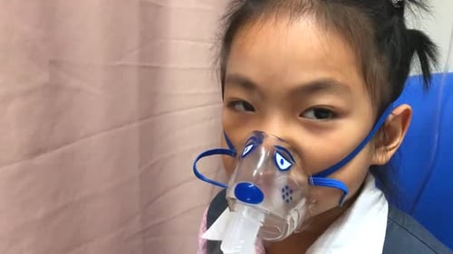 Asian little school girl making inhalation in Inhalation Mask.