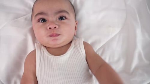 Sweet Infant Reaches Out From White Bed