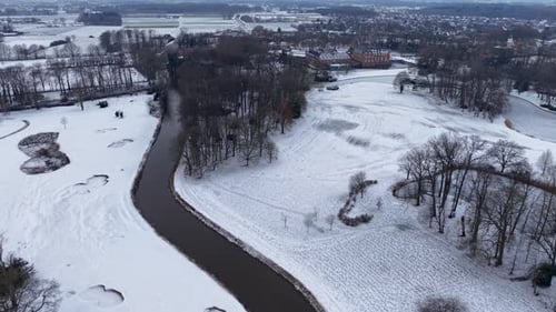 Aerial winter view of a winding river flowing through snowy fields and forests with scattered houses