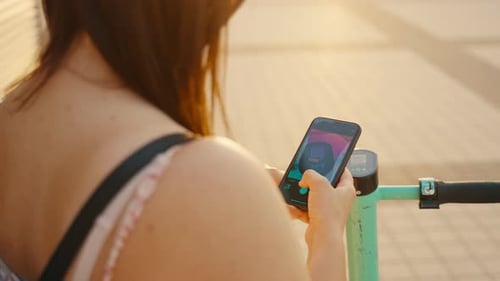 Woman Rents Electric Scooter Using Mobile Phone App at the Street