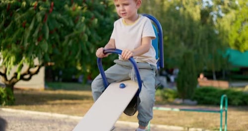 Little Boy Laughing and Having Fun Swinging on Seesaw Board Playing Playground