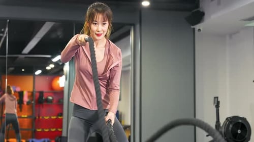 Fitnesstraining für muskulöse Frauen mit Battle Ropes, intensives Training, körperliche Kraft, Ausdauertraining.