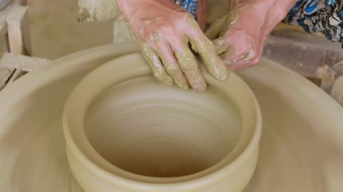 Finalisation d'un pot en argile sur une roue de potier manuelle avec du fil