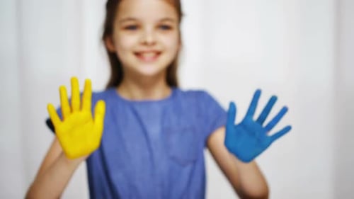 Smiling Girl with Painted Hands Raises Arms
