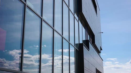 Clouds and Sky are Reflected in the Glass Windows of the Facade of an Office Building Stylish and