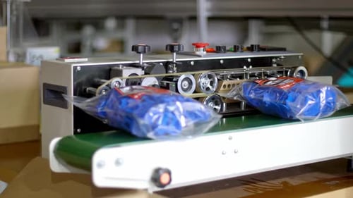 Sealing process as bags on conveyor belt get heat sealed by fast motion