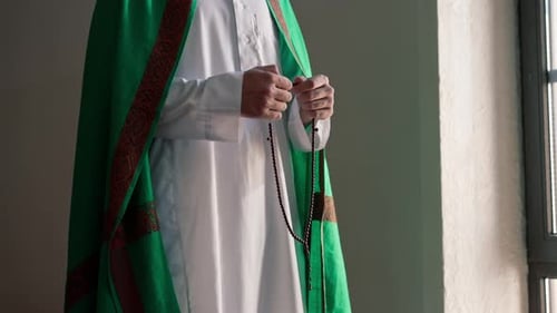 Adult Praying with Prayer Beads by a Window