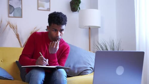 Young Man Studying With Laptop and Notebook at Home