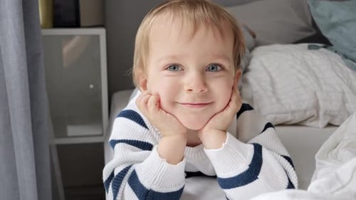 Child Lying on Bed Smiling and Playing
