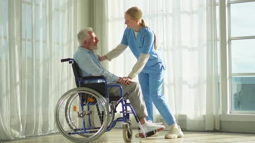 Caregiver Comforts Senior Man in Wheelchair Indoors