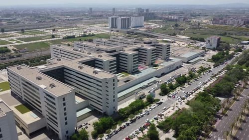 Aerial View Tilt Reveal of Hospital next to a busy road in Southern Spain