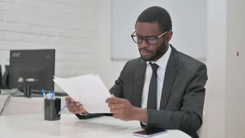 Thoughtful Businessman Reviewing Documents at office desk