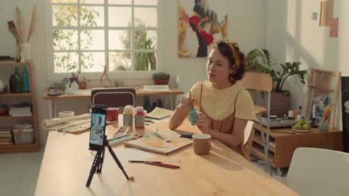 Mujer caucásica graba una lección de pintura para un blog en un teléfono inteligente