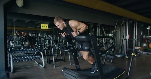 Junger Mann trainiert hart auf einem gebogenen Laufband im modernen Fitnessstudio