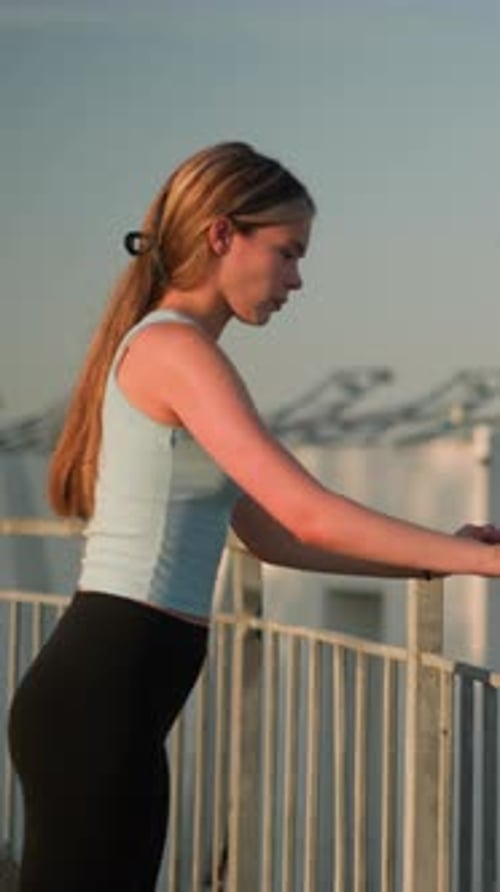 Young Lady Standing at Iron Railing Gazing Into Distance Under Sunlight