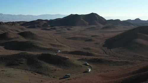 Revealing drone shot of a fleet of cars caravanning in the Charyn Canyon, Kazakhstan