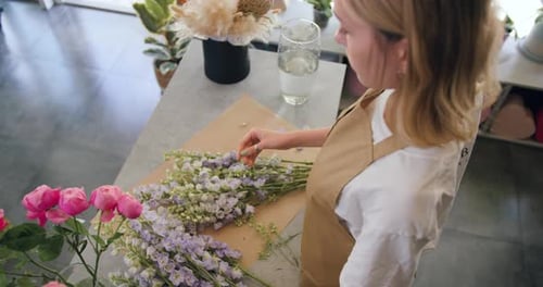 Une artiste fleuriste nettoie les fleurs pour un beau bouquet, vue de dessus sur le lieu de travail. Fleuriste en gros
plan