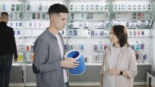 A Man and a Woman in a Consumer Electronics Store Choose a Portable Air Purification System and a
