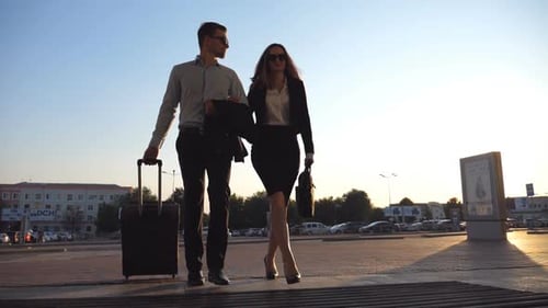 Businessman with His Female Colleague Walking Through Enter to Terminal and Roll Suitcase on Wheels