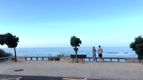 Young couple standing on viewpoint, looking at the Atlantic ocean