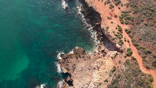 AERIAL: slowly tilting the camera up to reveal a beautiful coastline and sunset
