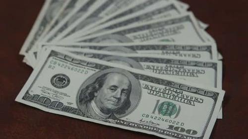 Pile of one hundred dollar bills on table
