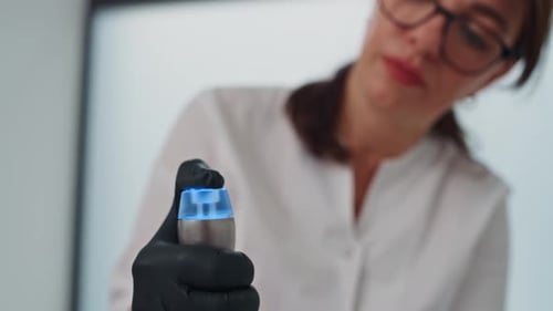 Cosmetologist Holding Modern Silver and Blue Skincare Device