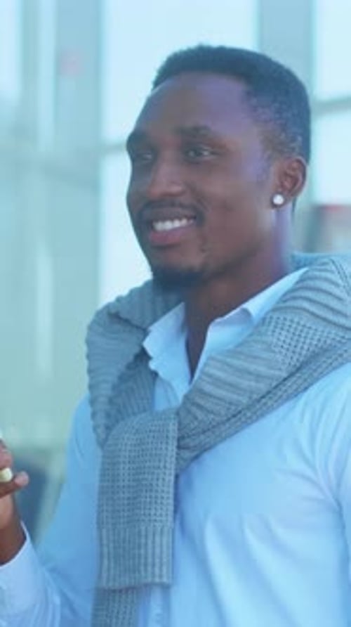 Smiling Man Holding Cellphone in Urban Outdoor Setting