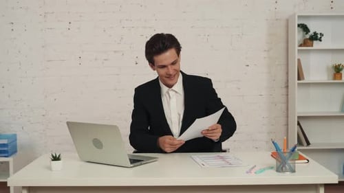 Medium Video of a Young Man in an Office Sitting in Front of His Laptop Getting a Video Call He