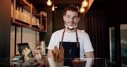 Smiling Young Adult Behind Cafe Counter