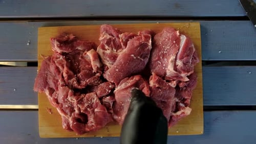 Preparing Raw Meat with Black Gloves and Salt