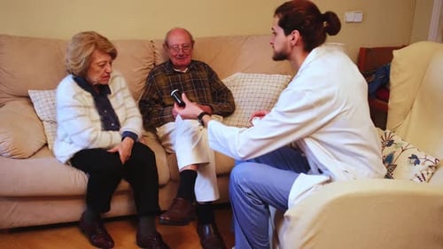 Health Professional Explaining Pills to Senior Couple at Home