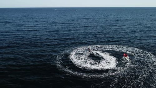 Jet Ski Tows Tube Riders in Ocean Aerial