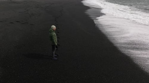 Man Standing on Black Sand Beach