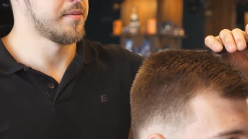 Close Up of Professional Male Hairstylist Combing Hair of His Customer in Trendy Barbershop