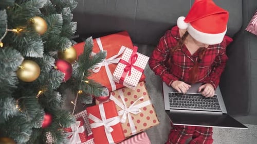 Woman in Pajamas Using Laptop Near Christmas Tree
