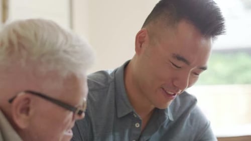 Man Helping Senior Man Reading Document Indoors