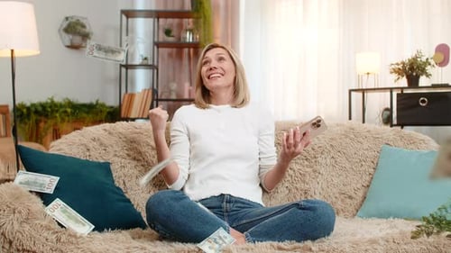 Woman on Couch Excited by Phone and Money