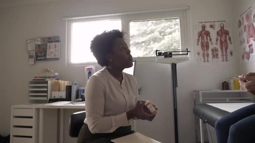 Female doctor explains prescription medicine to patient in hospital exam room