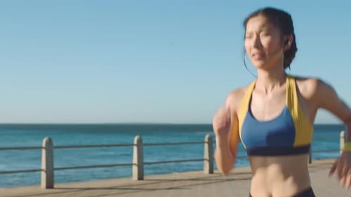 Asian woman, music earphone and running by ocean sea or water in Singapore healthcare wellness